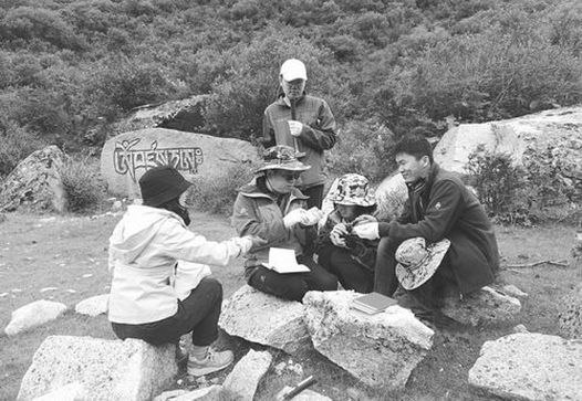 朱弟成(左二)向弟子们讲解岩石知识