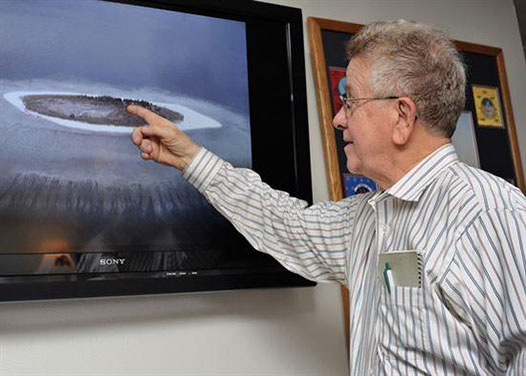 美军前测绘员鲍勃·坎宁安正在指着照片中的南海小岛，“北危岛”